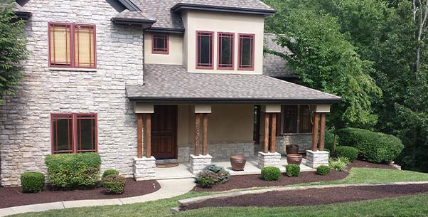 A freshly tilled and edged bed curving around a stone and brick house
